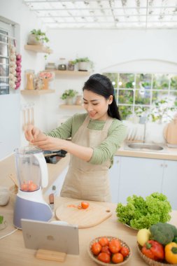 Güzel genç bayan tablette tarifiyle smoothie yapıyor.
