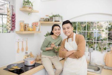 Mutlu genç çift mutfakta yemek yiyor ve konuşuyor.