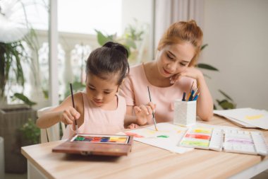 Genç Asyalı güzel anne ve kızı evde resim yapıyor..