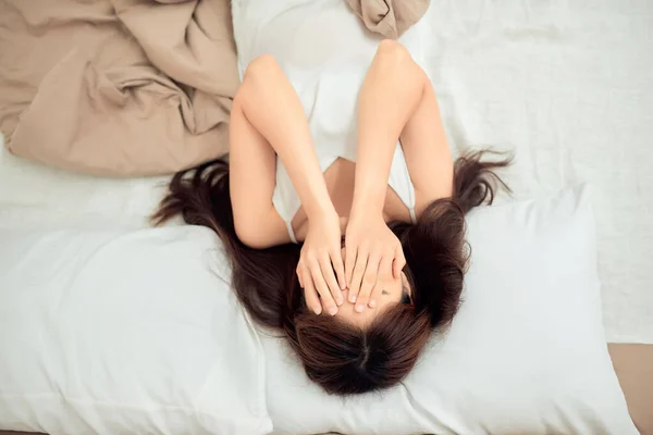 아름다운 아시아의한 여성은 침대에 머리를 조정하고 카메라를 봅니다 — 스톡 사진