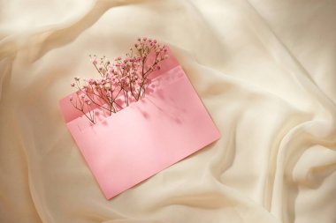Bahar çiçeği aranjmanlı pembe bir zarf. Düz yatış, üst görünüm