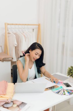 Genç bir Asyalı moda tasarımcısı atölyesinde çalışıyor.