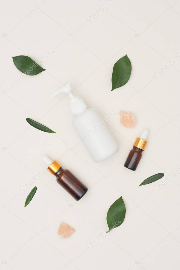 Serum or essential oil w/ organic herbal extract and skincare bottles on white background. Natural beauty cosmetic product. Top view