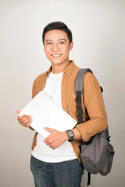 Portrait of Asian teenage college boy holding books and documents against white background