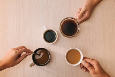Ahşap arka planda kahve fincanları tutan eller