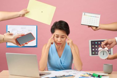 Overworked genç çalışan her şeyi reddeder, sıkıntı içinde yüz kaşlarını çatıyor, kağıt belgeler ve not defteri ile masaüstünde oturur, pembe arka plan üzerinde izole. Birçok soru dan rahatsız Kadın workes