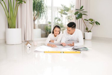 Mutlu çiftin evdeki planlara baktığı, kağıtta tasarım yapan bir ev.