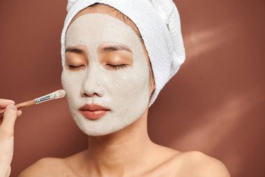 Çekici genç bir kadın yüzüne kozmetik maske takıyor..