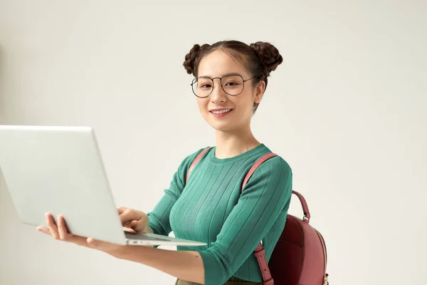 Portrait of a smiling girl holding laptop computer isolated on a white background and looking at camera
