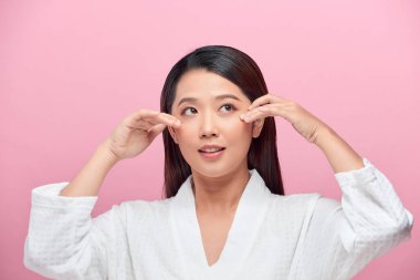 Güzel bir kızın pembe arka planda yüzüne dokunduğunu hayal et.