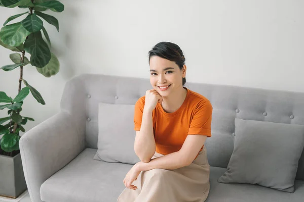 Young dreaming woman sitting on sofa at home.