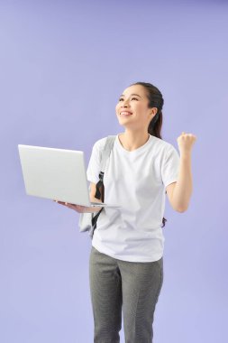 Güzel bir kız öğrenci sırt çantası takıyor ve dizüstü bilgisayar kullanıyor, kazanan konsept.