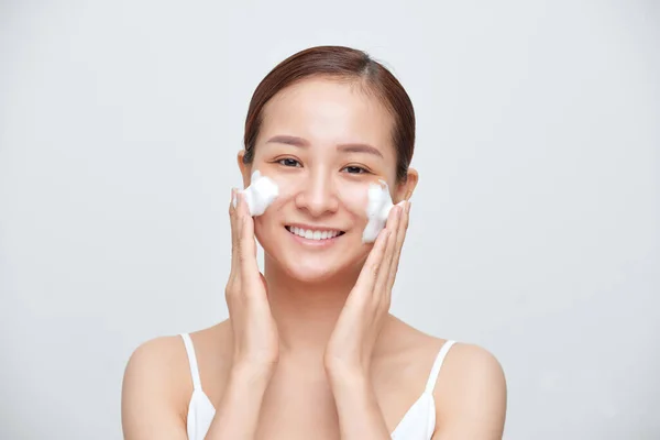 在白色背景下使用泡沫清洁剂的年轻亚洲妇女的画像 — 图库照片