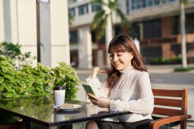 Kafede cep telefonundan mesaj okuyan Asyalı güzel bir kadının portresini kapat.