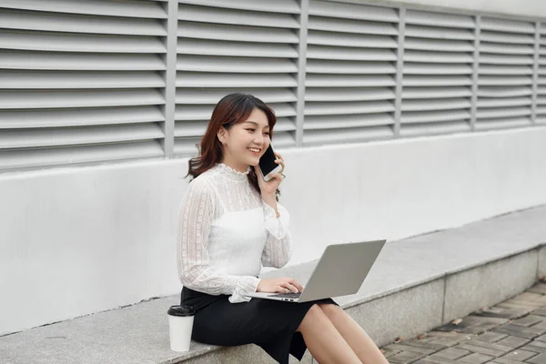 Asijské Žena Mluví Mobilním Telefonu Při Použití Notebooku — Stock fotografie