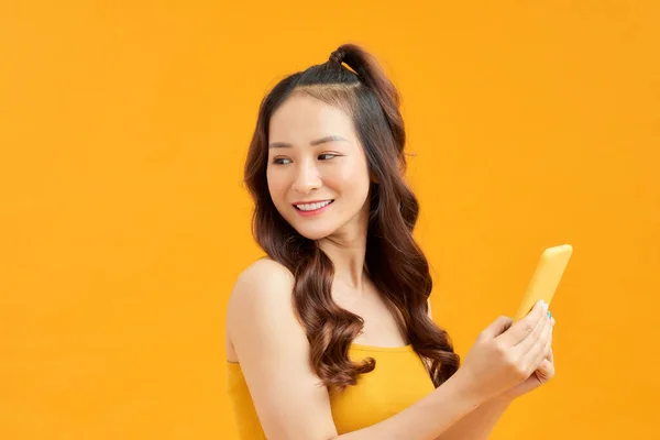 Mosolygó Fiatal Ázsiai Segítségével Okostelefon Elszigetelt Narancssárga Háttér — Stock Fotó