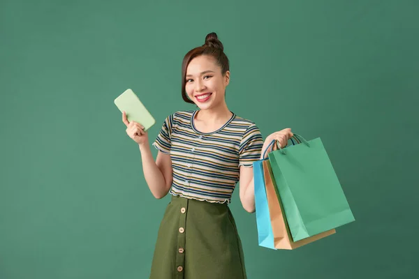 Jovencita Alegre Pie Sobre Fondo Verde Llevando Bolsas Compras Utilizando — Foto de Stock