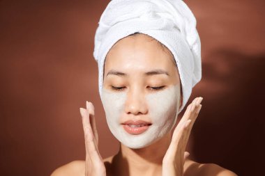Genç Asyalı kadın yüzüne kilden maske takıyor.. 