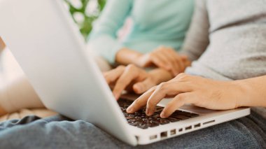 Genç Asyalı adam evde karısıyla birlikte dizüstü bilgisayar kullanıyor..