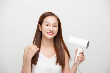 Güzel Asyalı kız saçını saç kurutma makinesiyle kurutuyor..