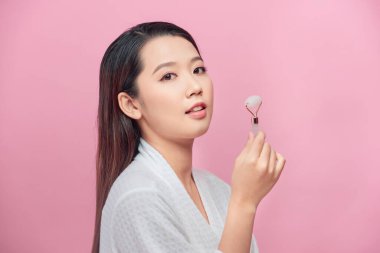 Güzellik yüz bakımı. Kadın yüz masajı yapıyor. Kaplıca cilt bakımı için yeşim yüz silindirleriyle.