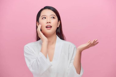 Temiz beyaz tenli güzel Asyalı kadın kendi yüzüne hafifçe dokunuyor..