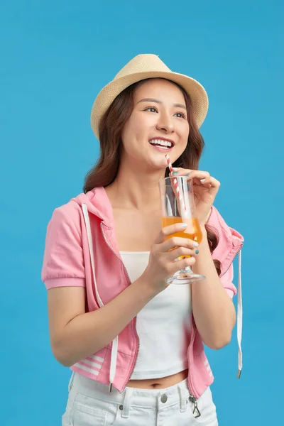 快乐的亚洲女人 穿着休闲装 喝着一杯蓝色背景的新鲜果汁 — 图库照片