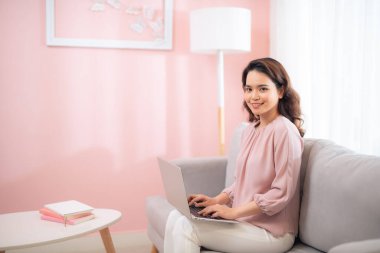 Kanepede oturan dizüstünü kullanarak çekici bir kadın yaşam tarzı.