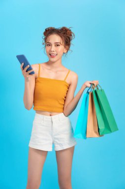 Akıllı bir telefon ve alışveriş torbası taşıyan mutlu bir müşteri.