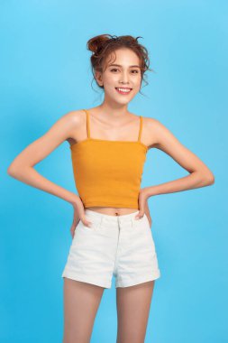 Şortlu ince bir portre ve mavi stüdyoda gülümseyen üstü açık bir resim.
