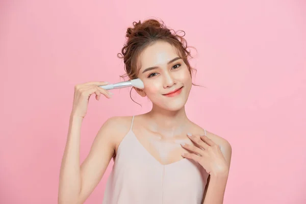 ゴージャスな若いです美しいですアジアの女性適用化粧絶縁上のピンクの背景 — ストック写真