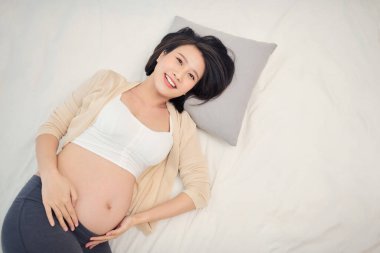 Güzel hamile kadın yatakta yatıyor.