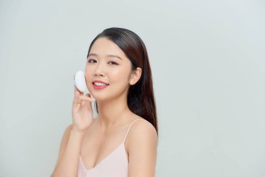 Yüzüne pudra pudrası süren genç bir bayan, cilt bakımı konsepti. 