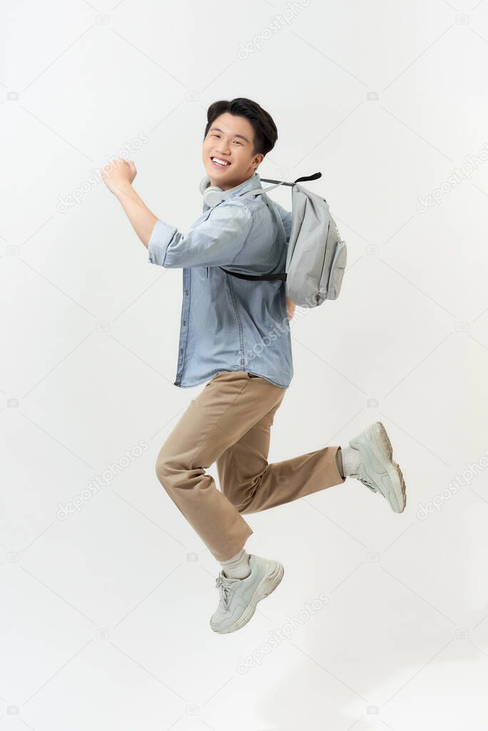 Full length portrait of a funny cheerful male student jumping on white background