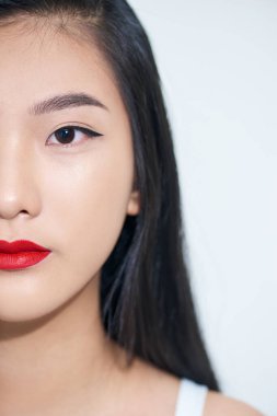 Güzel, gülümseyen bir kadının beyaz arka planda yarım yüz olarak kameraya bakışı..