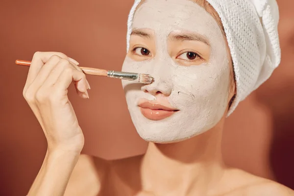 Szczęśliwa Kobieta Ręcznikiem Głowie Nakłada Maskę Oczyszczającą Twarz — Zdjęcie stockowe