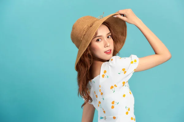 ファッショナブルなアジアの女性のイメージ20代の笑顔と触れわら帽子上の頭の上に隔離された青の背景 — ストック写真