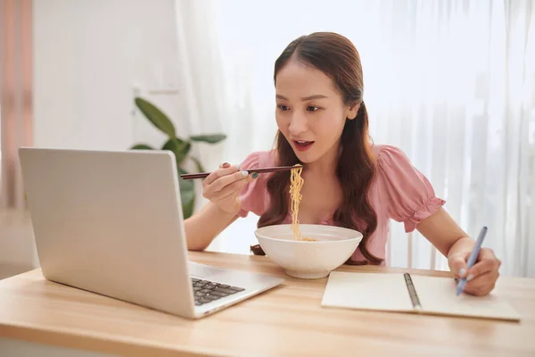Joven Mujer Asiática Comiendo Fideos Escribiendo Cuaderno Mientras Usa Ordenador — Foto de Stock