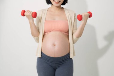 Hamile bir kadının odadaki dambıllarla egzersiz yaptığı yakın plan.