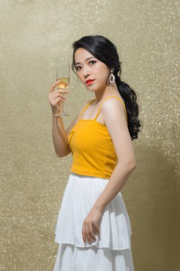 Genç mutlu bir kadın altın arka planda izole edilmiş şampanyayla gülümsüyor..