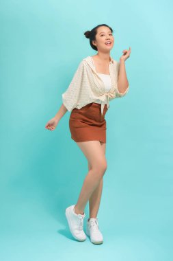 Neşeli, güzel bir kızın mavi arka planda izole edilmiş uzun bir portresi.