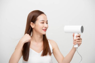 Çekici, güzel Asyalı kadın saç kurutma makinesiyle rüzgar üflüyor.