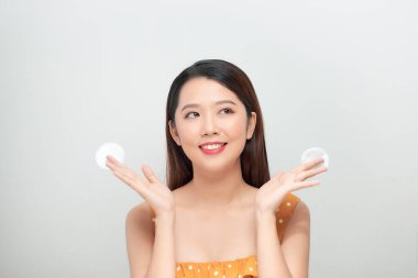 Beyaz arka planda izole edilmiş pamukla yüzünü temizleyen güzel kadın.