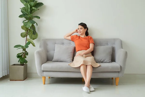 Young dreaming woman sitting on sofa at home.