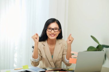 Ofiste dizüstü bilgisayarı olan gülümseyen bir kadın.