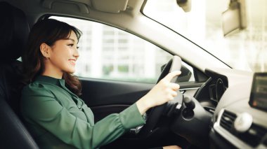 Genç ve güzel bir kadın arabasını kullanıyor.