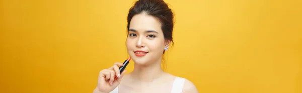 黄色の背景に赤いリップグロスを持つ美しいアジアの女性 — ストック写真