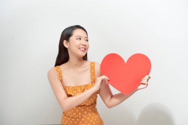 Büyük kırmızı kalp şeklinde gülümseyen Asyalı kız, başka tarafa bakıyor.