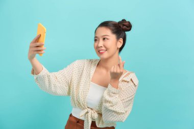 Akıllı telefonu mavi renkte tutan çekici kadın.