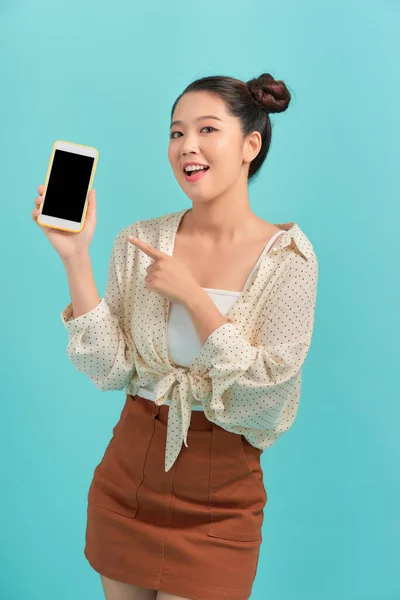 年轻漂亮的女人拿着蓝色背景的空白屏幕智能手机 — 图库照片